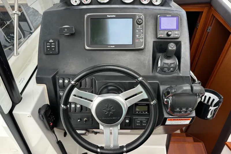 Slide: The Image of Control panel of a 2015 Jeanneau NC11 boat with steering wheel and navigation equipment. - 43