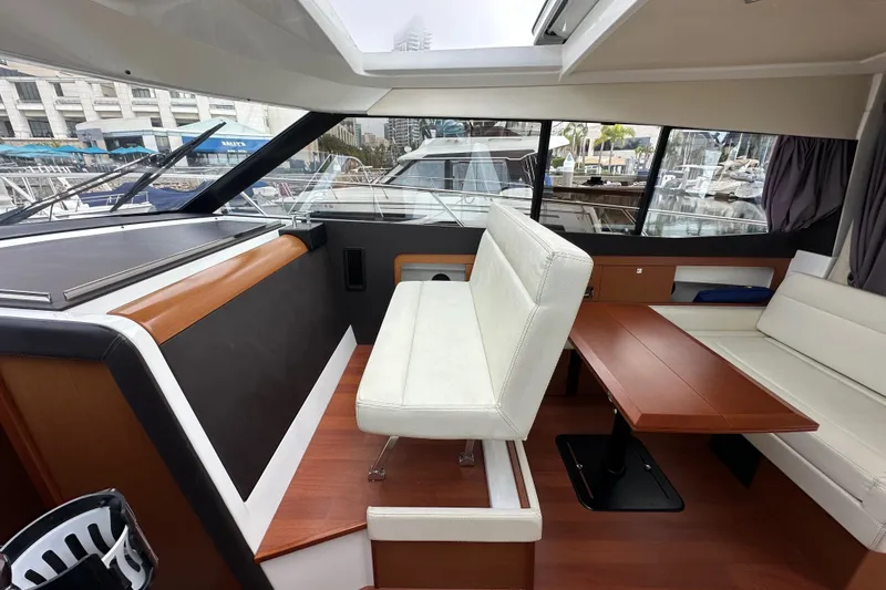 Slide: The Image of Interior of 2015 Jeanneau NC11 boat with seating and wooden table in marina setting. - 45