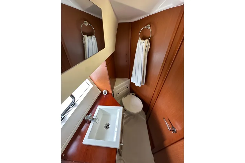 Slide: The Image of 2015 Jeanneau NC11 bathroom with sink, mirror, and wooden cabinetry. - 50