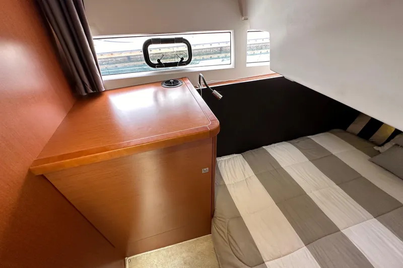 Slide: The Image of 2015 Jeanneau NC11 cabin interior with bed, wooden cabinetry, and window. - 54