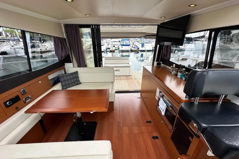 Slide: The Image of Interior of 2015 Jeanneau NC11 yacht with modern seating, table, and marina view. - 65