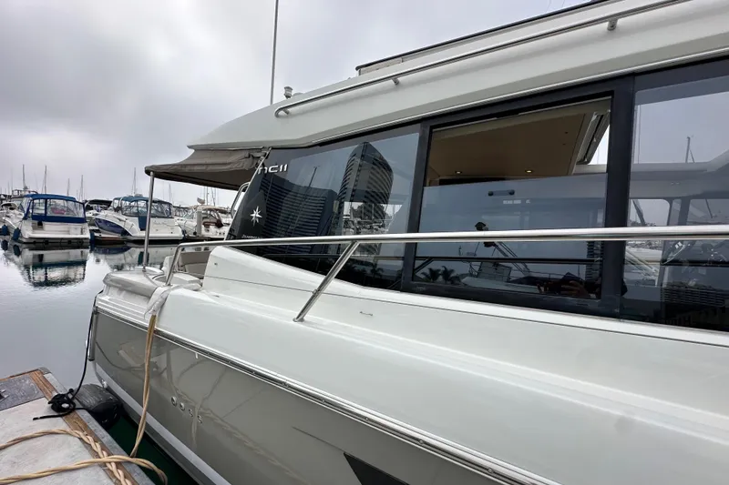 Slide: The Image of 2015 Jeanneau NC11 yacht docked at marina, side view with reflections on water. - 7