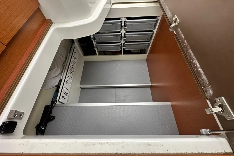 Slide: The Image of Storage compartment in a 2015 Jeanneau NC11 boat with organized bins and equipment. - 78