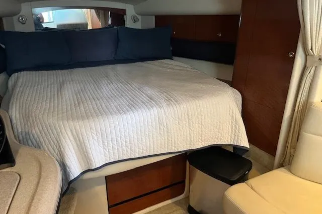 Slide: The Image of 2005 Sea Ray 320 Sundancer cabin with bed, wood accents, and seating area. - 17