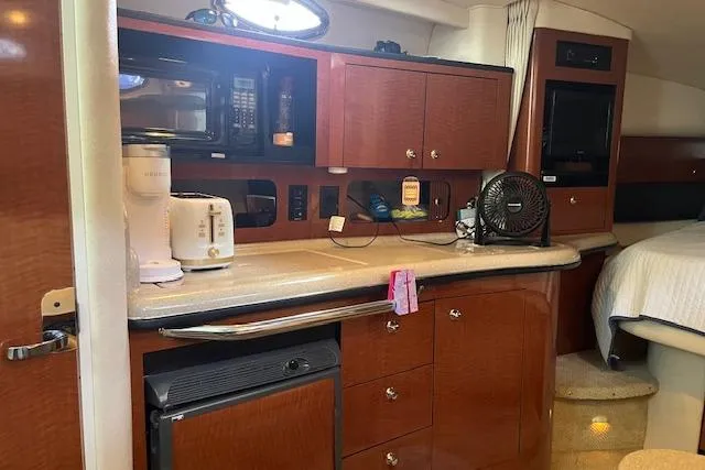 Slide: The Image of 2005 Sea Ray 320 Sundancer interior with kitchenette, featuring wood cabinets and modern appliances. - 18