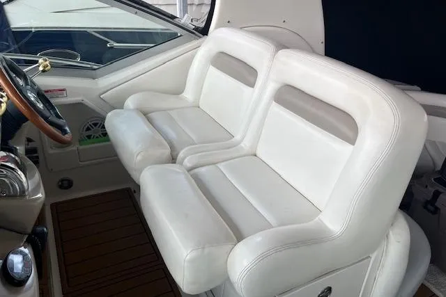 Slide: The Image of 2005 Sea Ray 320 Sundancer cockpit with white leather seats and wooden steering wheel. - 23