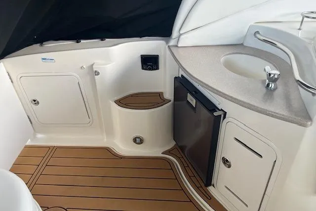 Slide: The Image of 2005 Sea Ray 320 Sundancer interior with sink, mini-fridge, and wood-style flooring. - 24