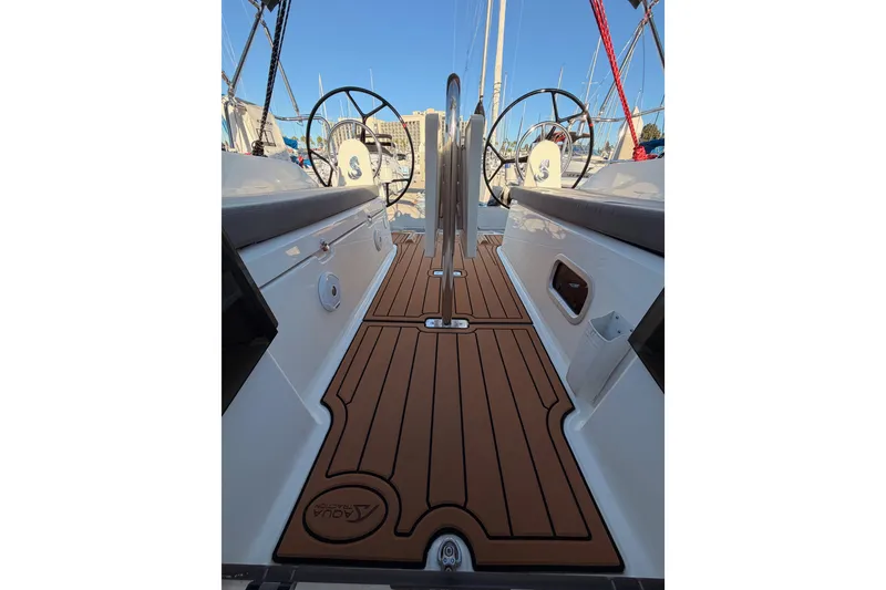 Slide: The Image of 2020 Beneteau Oceanis 30.1 yacht cockpit with dual steering wheels and teak flooring. - 58