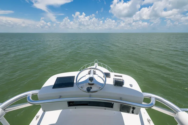 Slide: The Image of Helm view of 2010 Cabo 45 Express boat on open sea under blue sky. - 16