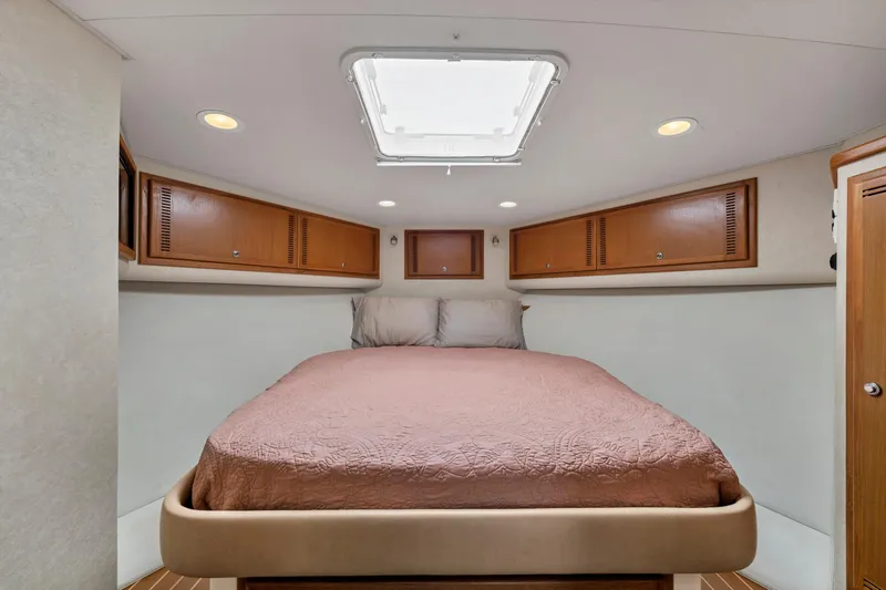 Slide: The Image of 2010 Cabo 45 Express cabin interior with bed, wooden cabinets, and ceiling hatch. - 25
