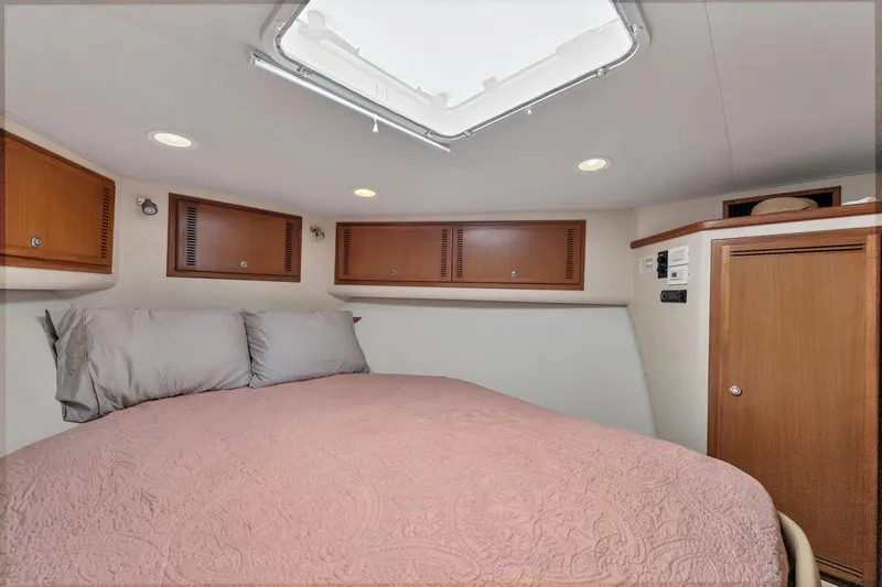 Slide: The Image of 2010 Cabo 45 Express cabin interior with bed, wooden cabinets, and ceiling hatch. - 26