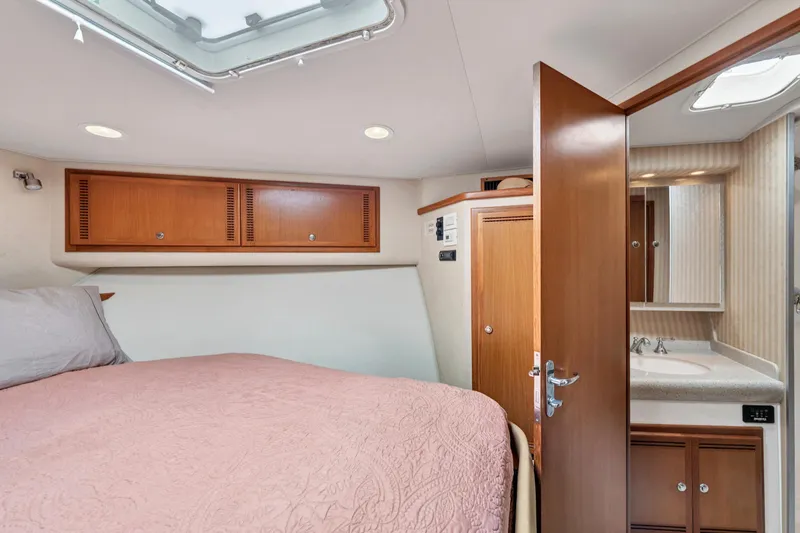 Slide: The Image of 2010 Cabo 45 Express cabin interior with bed, wooden cabinets, and bathroom. - 27