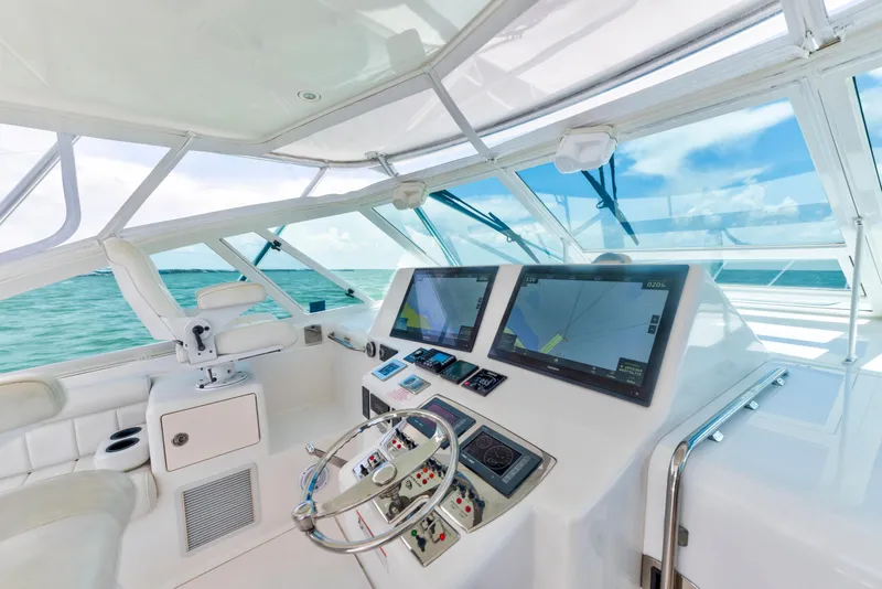 Slide: The Image of Helm of 2010 Cabo 45 Express yacht with dual navigation screens, steering wheel, and ocean view. - 7