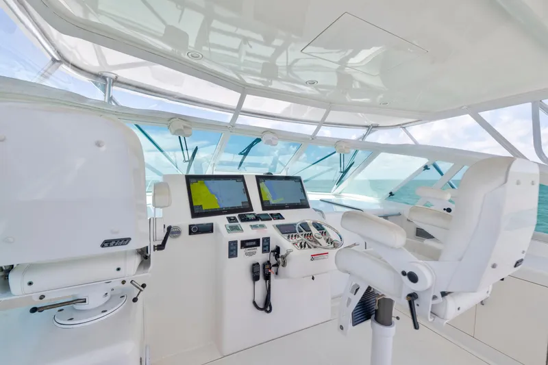 Slide: The Image of 2010 Cabo 45 Express helm with navigation screens and white captain's chairs. - 8