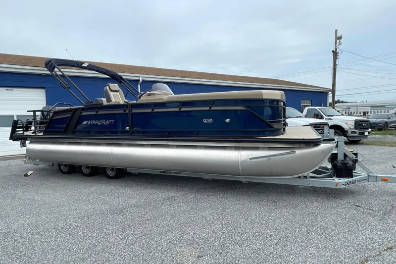 Slide: The Image of 2026 Starcraft EXS 5 Q DH pontoon boat on trailer, blue and beige design. - 2