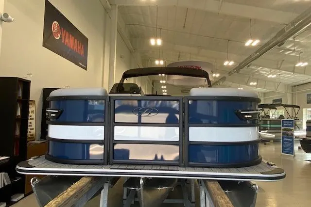 Slide: The Image of 2026 Bentley Pontoons Elite 223 Swingback in showroom, blue and white exterior. - 2