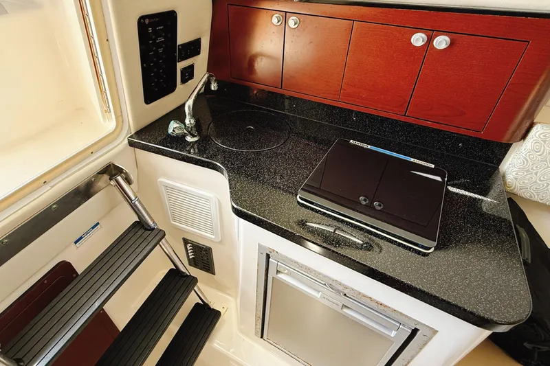 Slide: The Image of 2016 Century 2600 Walkaround boat interior with kitchenette and wooden cabinets. - 26