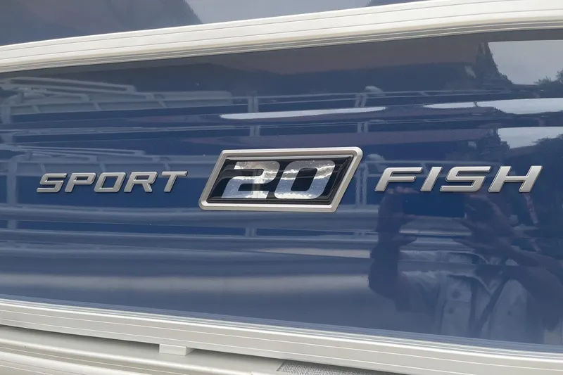 Slide: The Image of 2026 Sun Tracker SportFish 20 DLX boat logo on blue surface. - 6