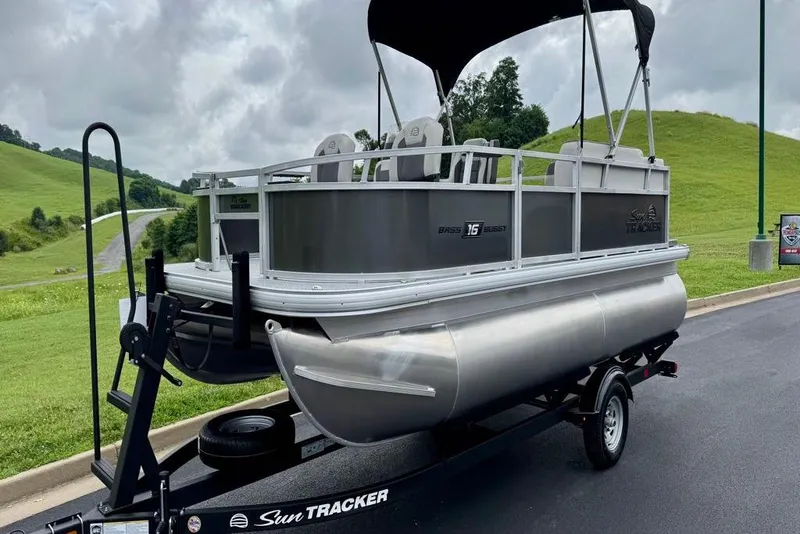 Slide: The Image of 2026 Sun Tracker Bass Buggy 16 XL Select pontoon boat on trailer, scenic background. - 4