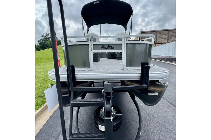 Slide: The Image of 2026 Sun Tracker Bass Buggy 16 XL Select pontoon boat on trailer, scenic background. - 6