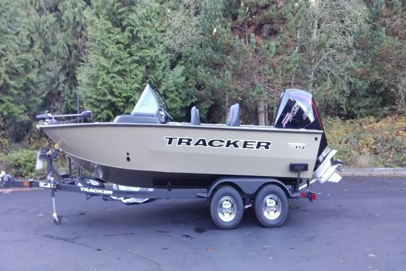 The Image of 2026 Tracker Targa V-19 Combo boat on trailer, parked near lush green trees. - 0