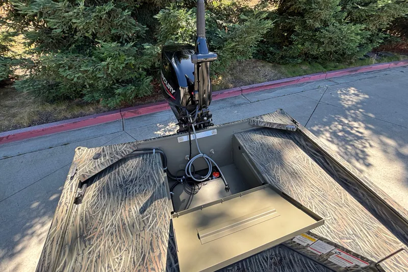 Slide: The Image of 2026 Tracker Grizzly 1654 T Sportsman boat with Mercury outboard motor, parked on pavement. - 17