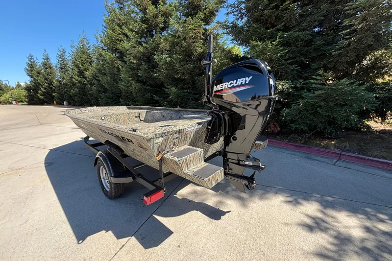 Slide: The Image of 2026 Tracker Grizzly 1654 T Sportsman boat with Mercury engine, parked outdoors. - 7