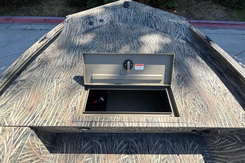 Slide: The Image of 2026 Tracker Grizzly 1654 T Sportsman boat with open storage compartment, camo pattern. - 9