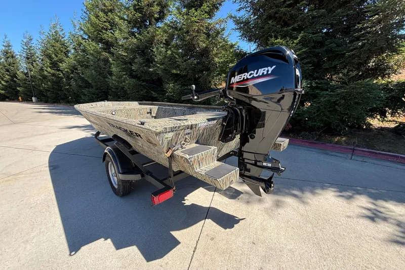Slide: The Image of 2026 Tracker Grizzly 1654 T Sportsman boat with Mercury engine, parked outdoors. - 5
