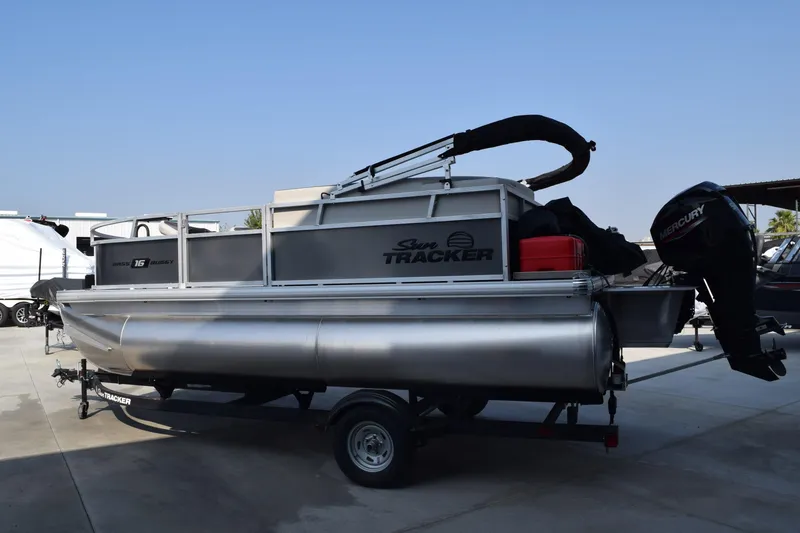 The Image of 2026 Sun Tracker Bass Buggy 16 XL Select pontoon boat on trailer, outdoor setting. - 0
