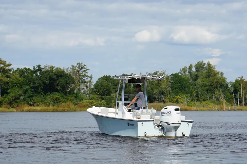 Slide: The Image of 2023 Maycraft 2100 CC boat cruising on a calm river with lush green trees. - 5