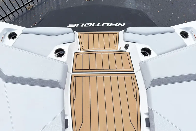 Slide: The Image of 2025 Nautique Super Air Nautique S21 boat deck with cushioned seating and cup holders. - 10