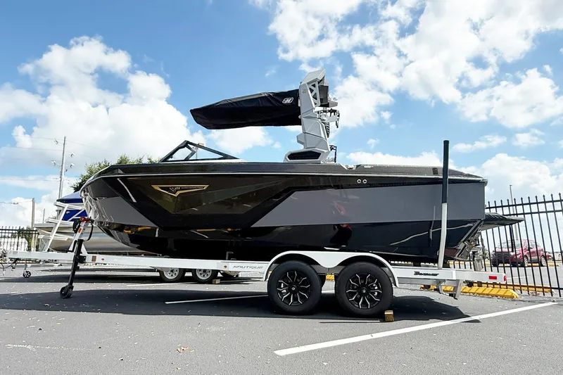 Slide: The Image of 2025 Nautique Super Air Nautique S21 boat on trailer under blue sky. - 3