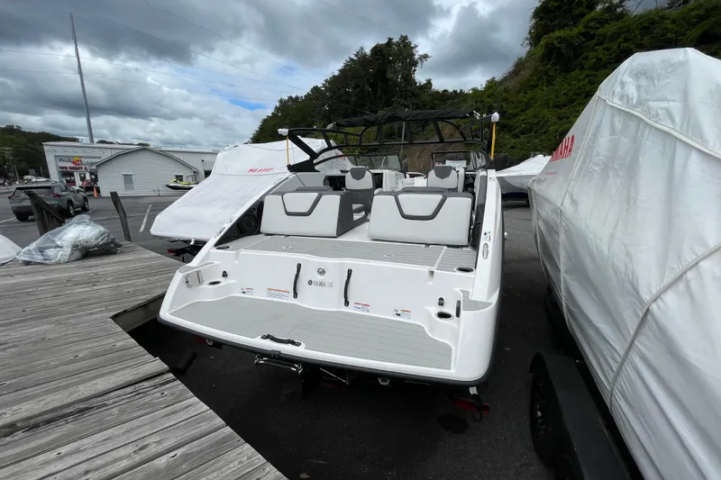 Slide: The Image of 2026 Yamaha AR250 boat docked, rear view, with covered boats nearby. - 20