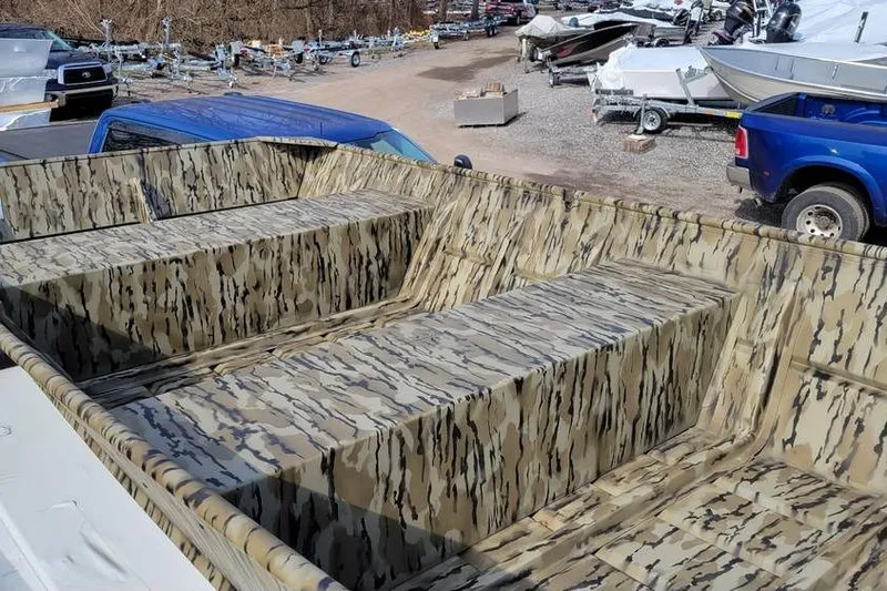 Slide: The Image of 2025 Smoker Craft Jon Boat 1448 with camouflage interior, parked outdoors. - 8