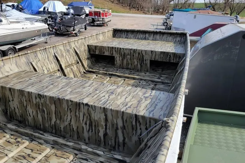 Slide: The Image of 2025 Smoker Craft Jon Boat 1448 with camouflage design in a boatyard. - 9