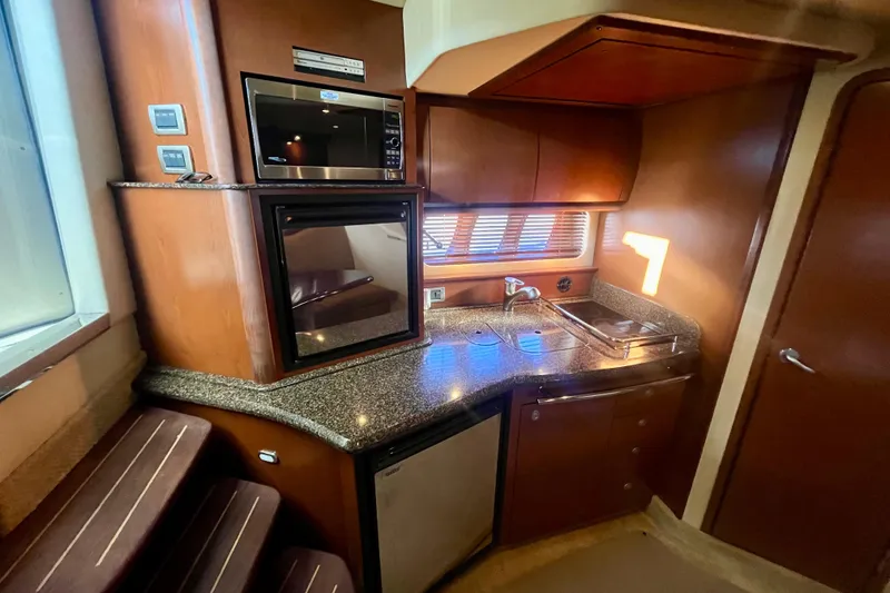 Slide: The Image of 2007 Sea Ray 38 Sundancer yacht interior kitchen with microwave, sink, and wooden cabinetry. - 8