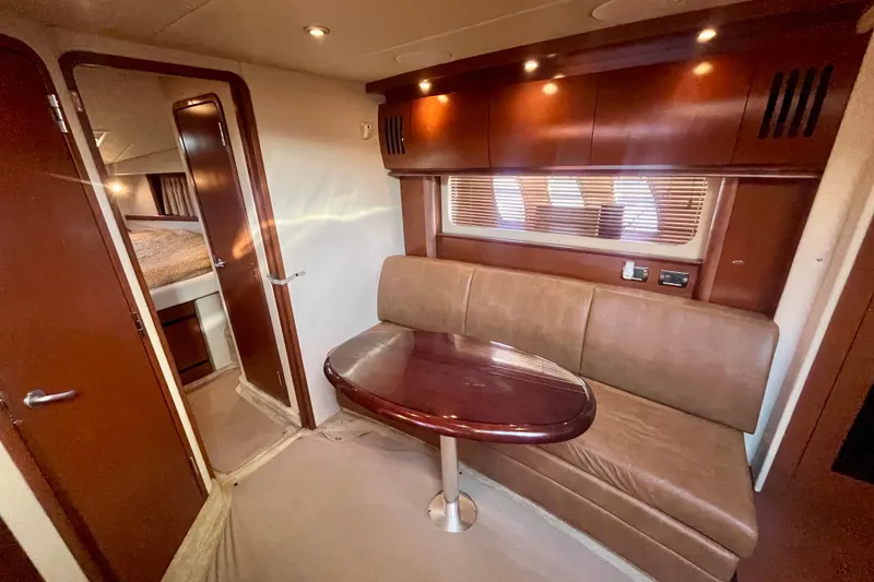 Slide: The Image of Interior of 2007 Sea Ray 38 Sundancer with leather seating and wooden table. - 9