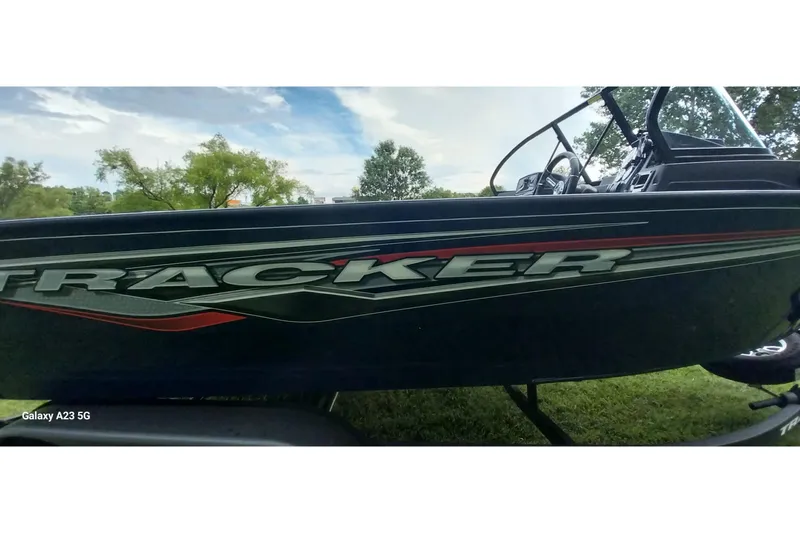 Slide: The Image of 2024 Tracker Targa V-18 Combo boat side view with logo, parked on grass. - 10