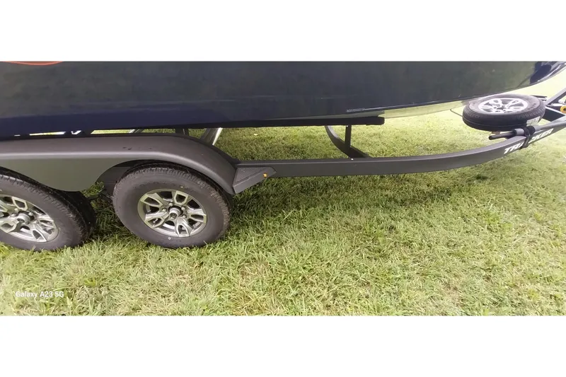 Slide: The Image of 2024 Tracker Targa V-18 Combo trailer on grass, showcasing dual wheels. - 11