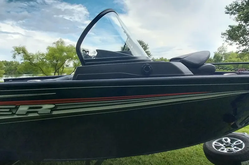 Slide: The Image of 2024 Tracker Targa V-18 Combo boat, sleek design, parked on grass with scenic background. - 17