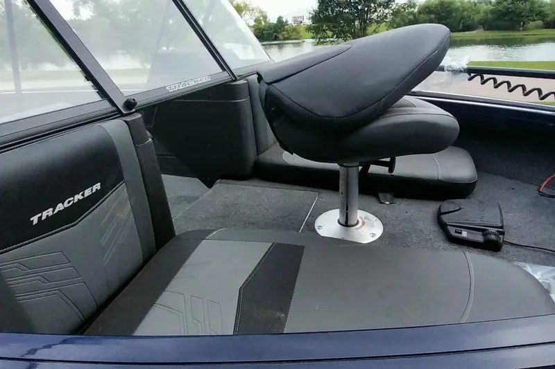 Slide: The Image of 2024 Tracker Targa V-18 Combo boat interior with seating and console, near a lake. - 21