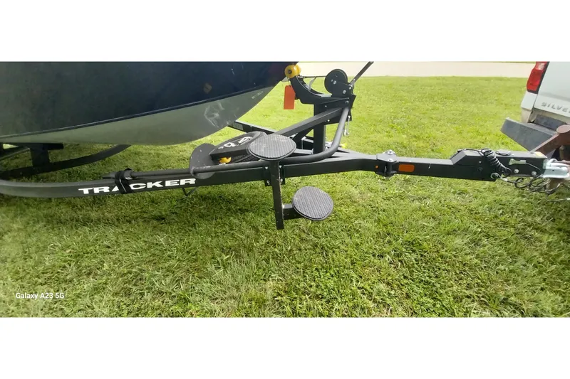 Slide: The Image of 2024 Tracker Targa V-18 Combo boat trailer on grass, featuring sturdy hitch and steps. - 24