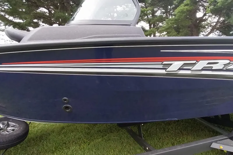 Slide: The Image of 2024 Tracker Targa V-18 Combo boat with sleek blue and red design on a trailer. - 33