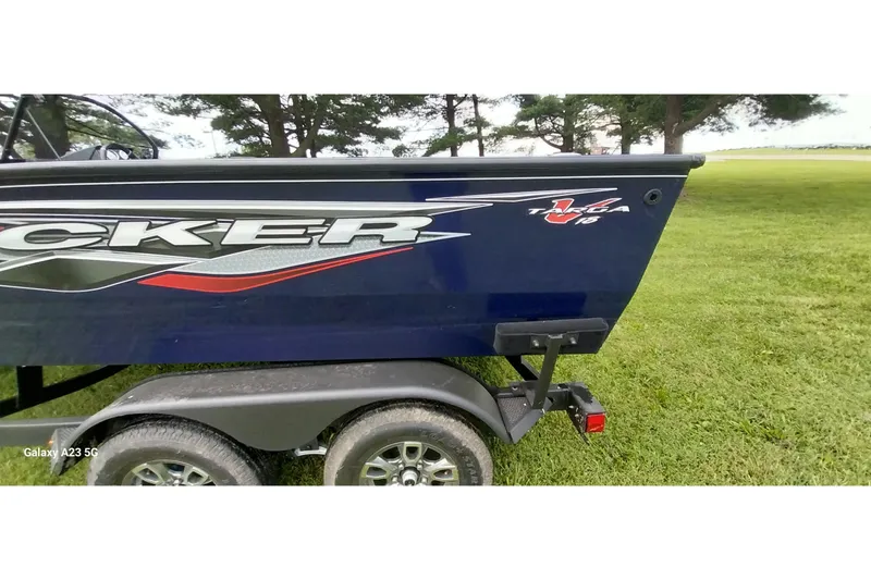 Slide: The Image of 2024 Tracker Targa V-18 Combo boat on trailer, parked on grassy area. - 41