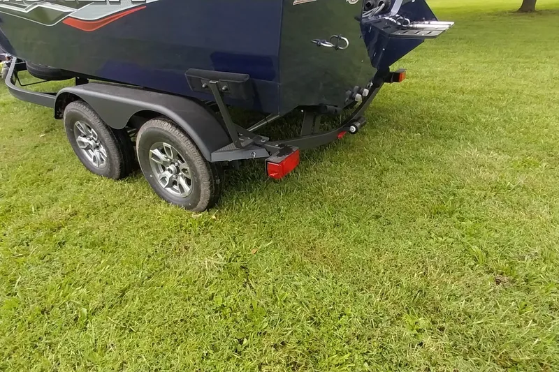 Slide: The Image of 2024 Tracker Targa V-18 Combo boat trailer on grass, showcasing dual wheels. - 44