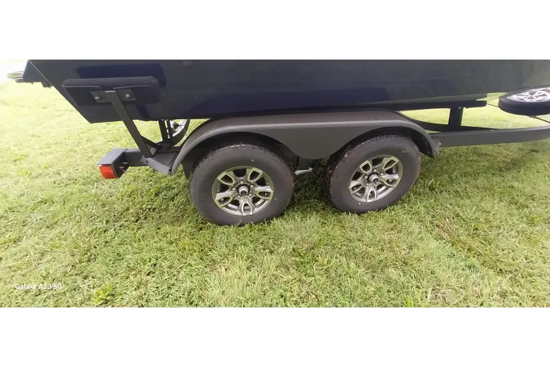 Slide: The Image of 2024 Tracker Targa V-18 Combo trailer with dual wheels on grass. - 6