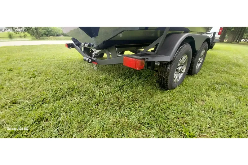 Slide: The Image of 2024 Tracker Targa V-18 Combo trailer on grass, showcasing dual wheels and rear view. - 7