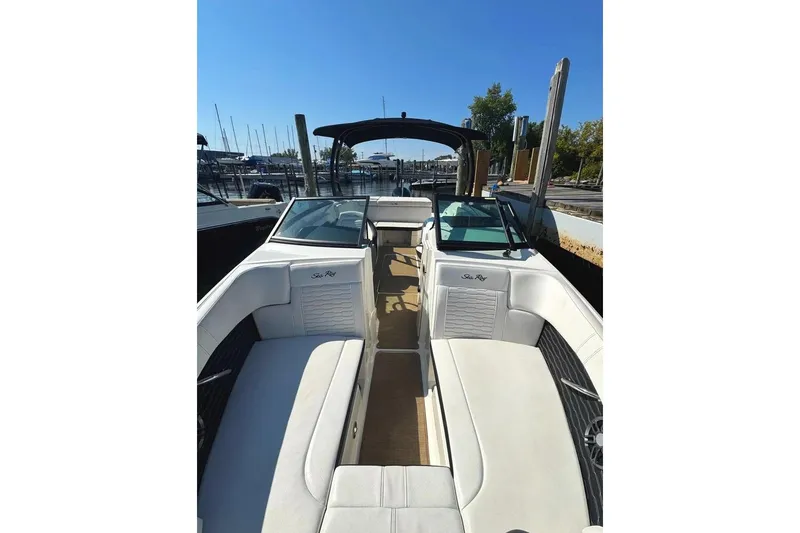 Slide: The Image of 2022 Sea Ray SPX 230 Outboard boat interior with white seating and marina background. - 11