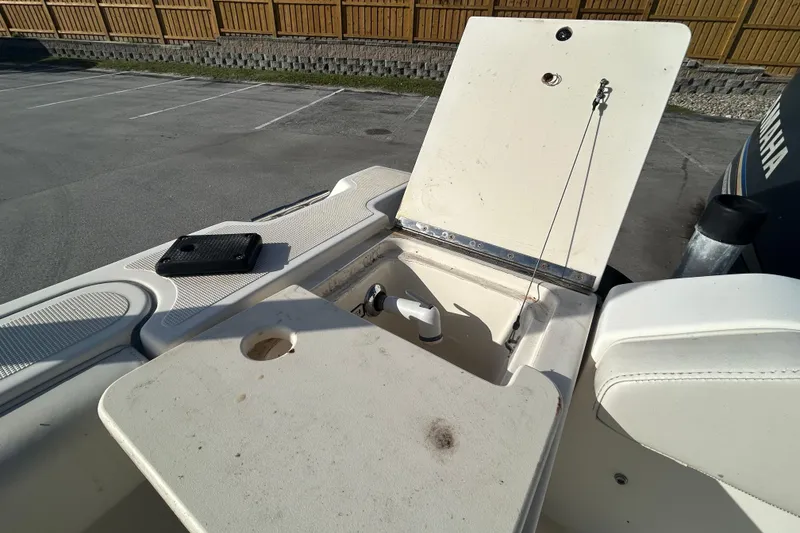 Slide: The Image of 2000 Pursuit 2470 Walkaround boat with open storage compartment and Yamaha engine in parking lot. - 10